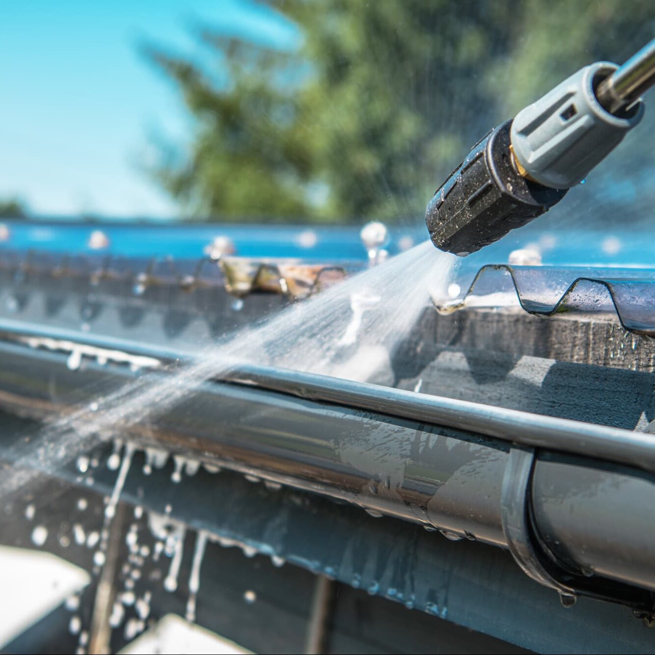 Close up of power washer cleaning out gutters